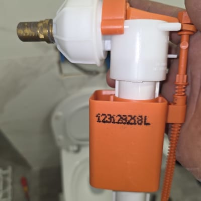 שסתום פלסטיק כתום ולבן ליד אסלה