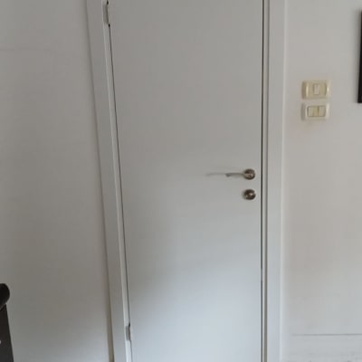 דלת לבנה עם ידית כסופה על קיר לבן