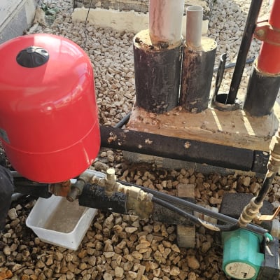 אדם עובד על דוד שמש עם מיכל אדום וצינורות.