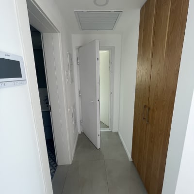 מסדרון עם דלתות לבנות וארון עץ