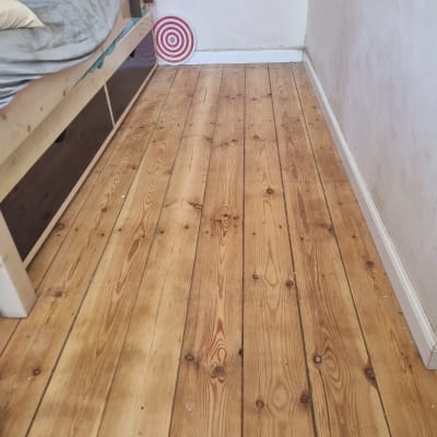 רצפת עץ בחדר עם מיטה ויעד קליעה למטרה