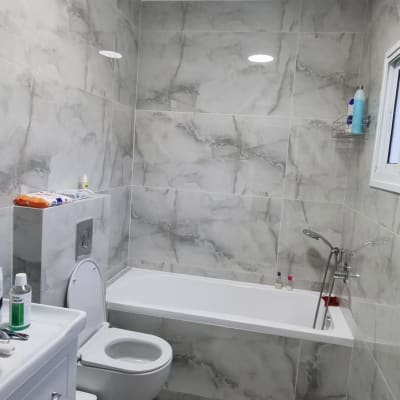 חדר אמבטיה משופץ עם אריחים אפורים ואמבטיה חדשה