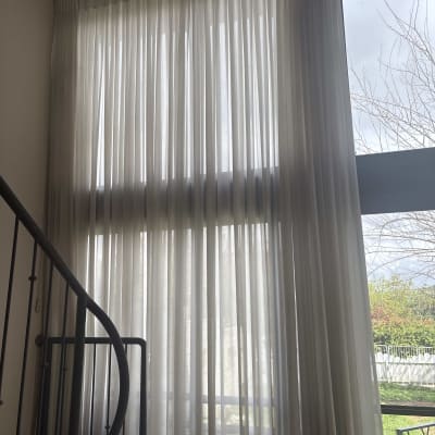 וילון לבן תלוי על חלון גדול ליד מדרגות