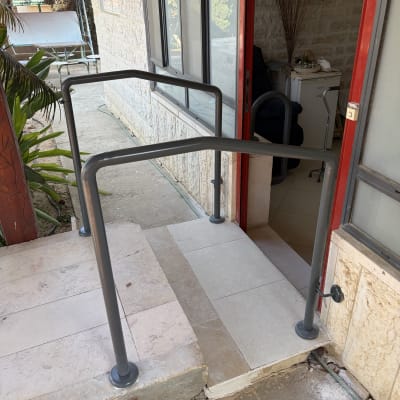 מעקה מתכת ליד כניסה לבית עם שביל מרוצף