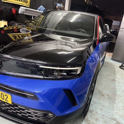 רכב כחול ושחור בחלל עבודה עם שלט 