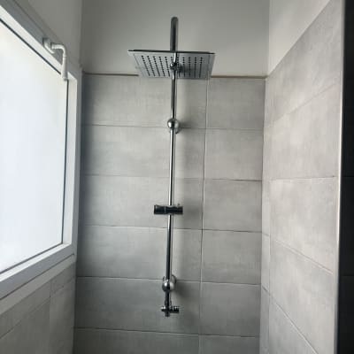 ראש מקלחת מותקן על קיר אריחים אפורים