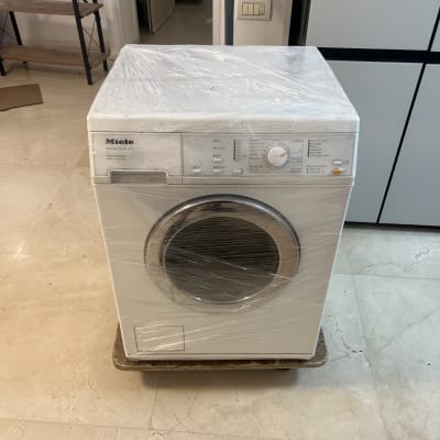מכונת כביסה עטופה בניילון על משטח עץ