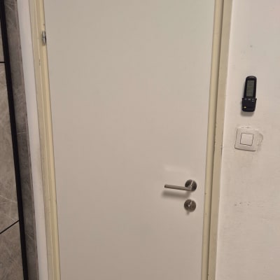דלת פנים לבנה עם ידית מתכת על קיר לבן