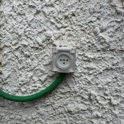 שקע חשמלי מותקן על קיר עם צינור ירוק