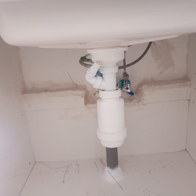 כיור עם צנרת פלסטיק לבנה מתחת לשיפוץ