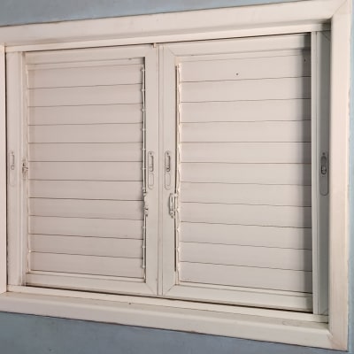 חלון עם תריסים לבנים סגורים ומסגרת לבנה