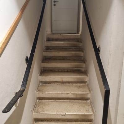 מדרגות עם מעקה שחור ודלת לבנה