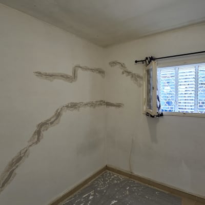 קיר עם תיקוני טיח ויריעת מגן על הרצפה