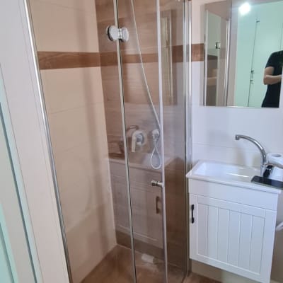 מקלחון זכוכית עם ראש מקלחת וכיור לידו