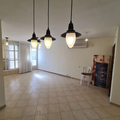 חדר ריק עם מנורות תלויות ותמונה על הרצפה