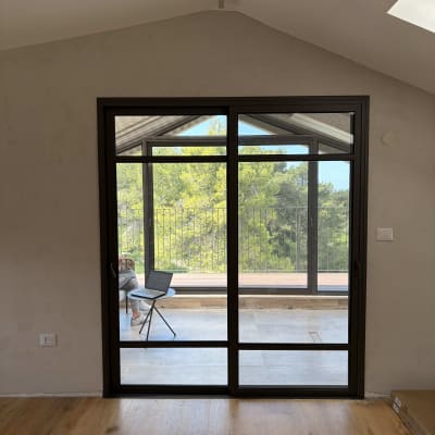 חלון אלומיניום עם נוף חיצוני ועץ ברקע