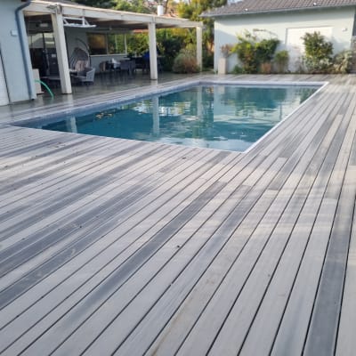 בריכת שחייה עם דק עץ מסביב, גינה ובית ברקע