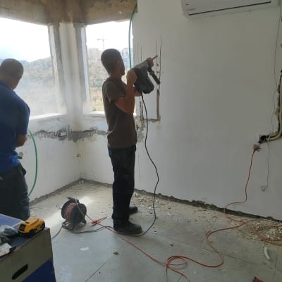 חשמלאי קודח בקיר עם מקדחה חשמלית