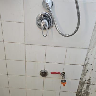 ברזים ומקלחת על קיר אריחים לבנים