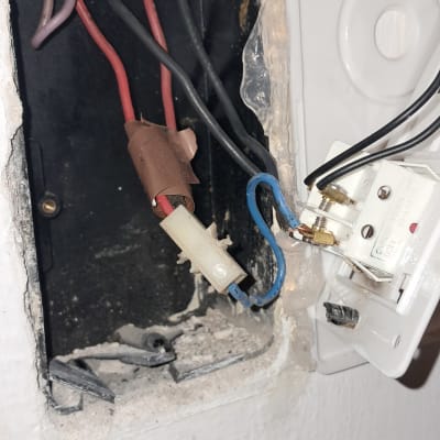 חוטי חשמל חשופים בקופסת חיבורים בקיר