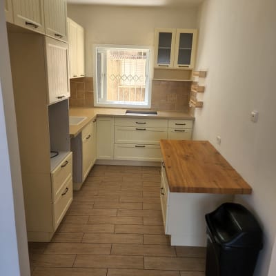 מטבח נקי עם ארונות, משטח עבודה ופח אשפה