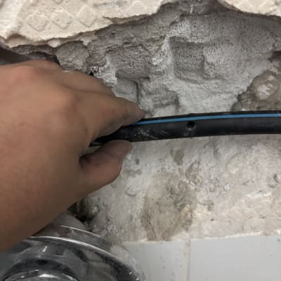 יד מחזיקה צינור ליד קיר שבור