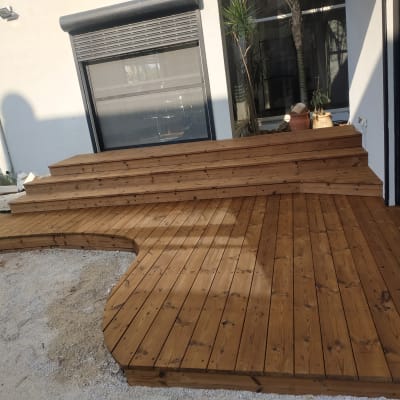 דק עץ חום עם מדרגות ליד קיר חיצוני