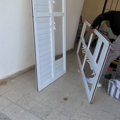 אדם מתקין תריסים לבנים על הרצפה