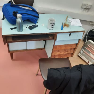 תיק כחול, בקבוק מתכת, כוס קפה על שולחן