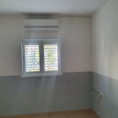 מזגן מותקן על קיר מעל חלון עם תריסים