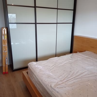 מיטה עטופה בניילון ליד ארון הזזה וסולם