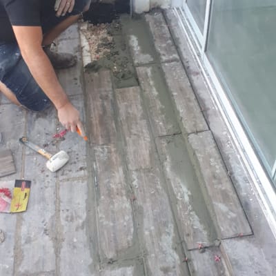 אדם מורח חומר איטום בין אריחי רצפה