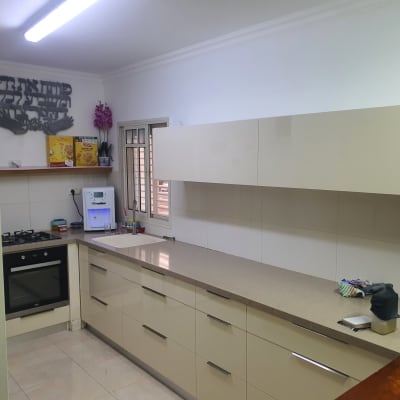 מטבח עם ארונות בהירים, כיור ובר מים על השיש