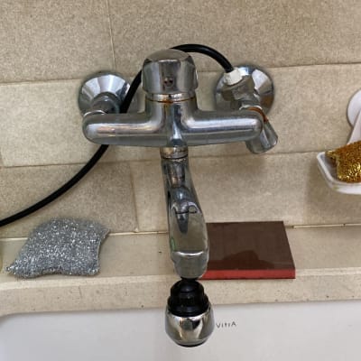 ברז מתכת עם צינור שחור מעל כיור לבן