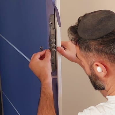 אדם מתקין ציפוי לדלת כחולה עם פסי מתכת