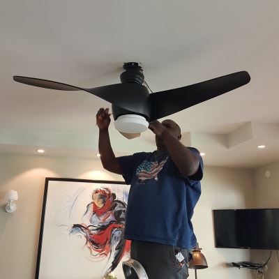 חשמלאי מתקין מאוורר תקרה עם כלי עבודה