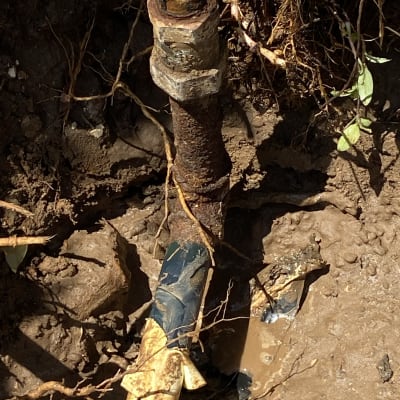 צינור חלוד עם נזילה באדמה רטובה