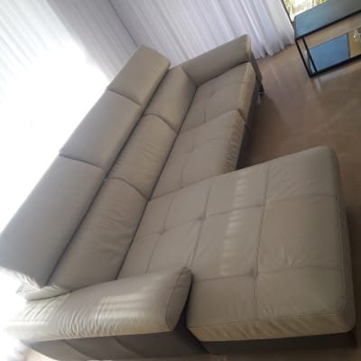 ספה בהירה ליד חלון עם וילונות לבנים