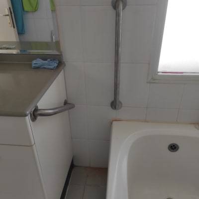 ידית אחיזה מתכתית ליד אמבטיה בחדר רחצה