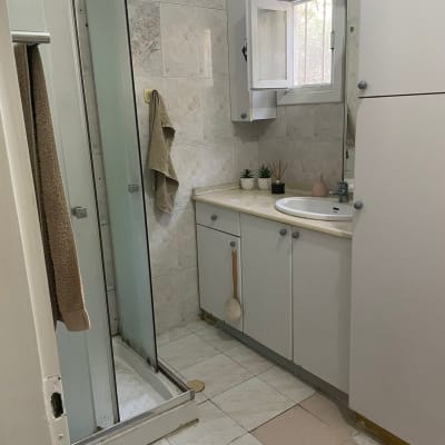 חדר אמבטיה עם מקלחון, ארון כיור, אריחים חסרים