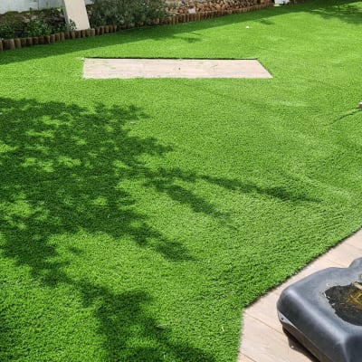 דשא סינתטי עם צללים וכלי גינון על הקרקע