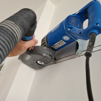כלי עבודה חשמלי כחול חותך קיר לבן