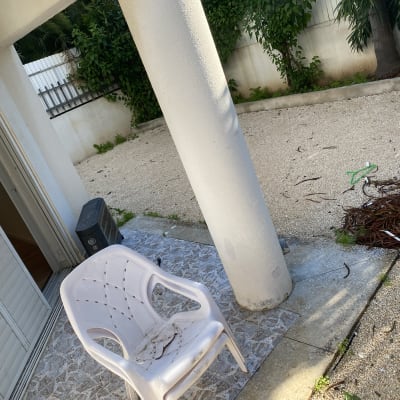 כיסא פלסטיק מלוכלך, מטאטא ירוק, ערימת ענפים על הקרקע