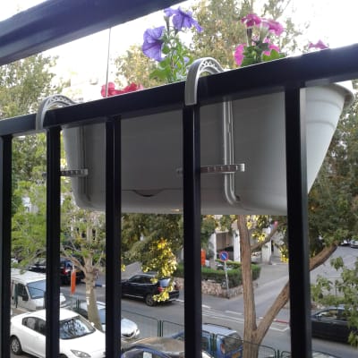 עציץ תלוי על מעקה עם פרחים סגולים וורודים