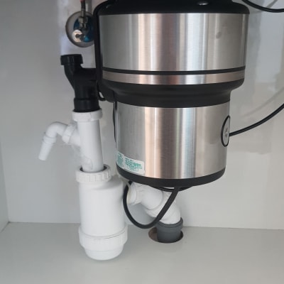 מתקן טוחן אשפה מתחת לכיור עם צינורות חיבור