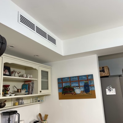 פתחי אוורור של מזגן בתקרה לבנה במטבח.