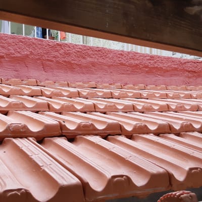 רעפים כתומים על גג עם קיר ורוד ברקע