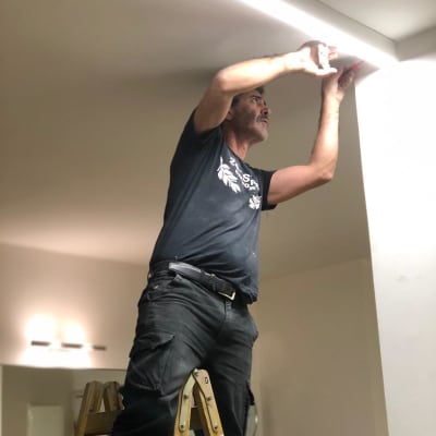 חשמלאי עובד על תאורה בתקרה בעזרת סולם