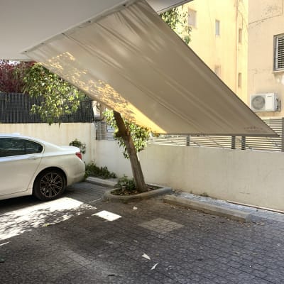 סוכך בד בזווית מעל חניה לרכב