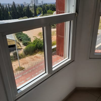 חלון פתוח עם מסגרת לבנה וקיר נקי